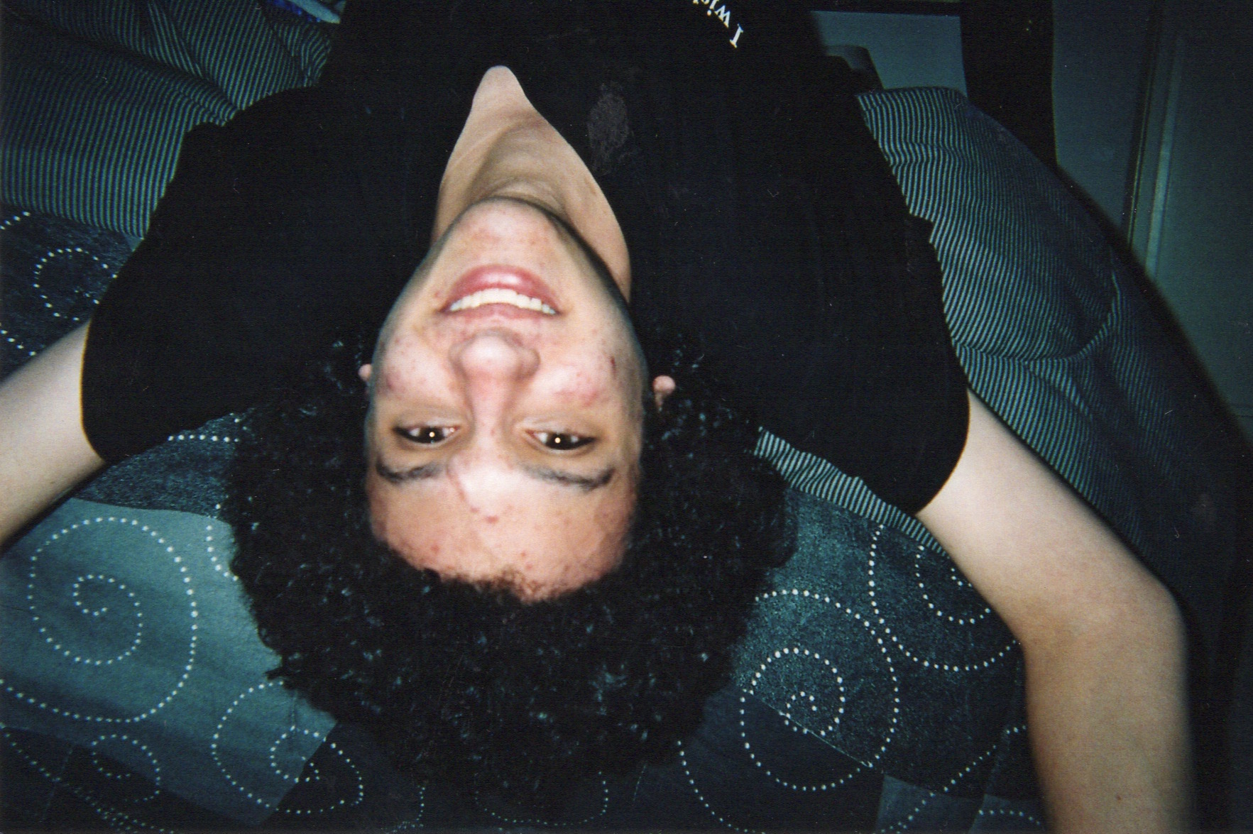 Matthew, smiling and lying upside down on my bed